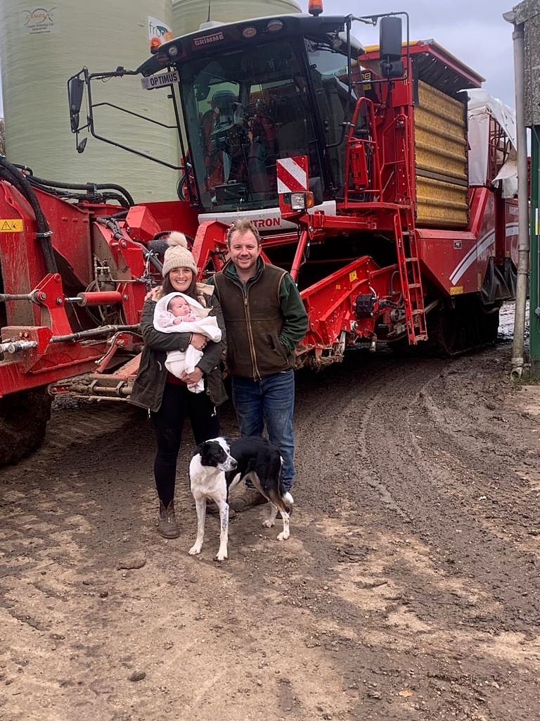 Sam and his family with their dog beside red farm machinery